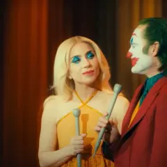 La femme du Joker, avec son maquillage bleu scintillant, semble chanter face à lui, le clown au visage blanc et rouge.