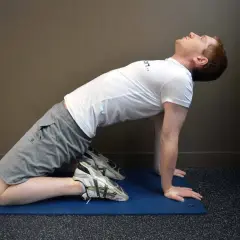 Homme en position de yoga, genoux au sol, mains à plat, effectuant un étirement quadriceps profond pour améliorer la flexibilité.