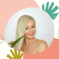 Kobieta z blond włosami dotyka ich liściem aloesu, odkrywając jego pielęgnacyjne właściwości. Aloes na włosy to sekret piękna.