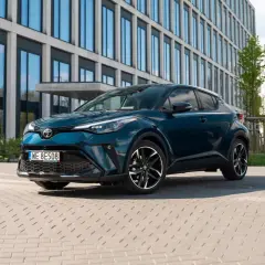 Elegancka, ciemnozielona Toyota hybryda na tle nowoczesnych budynków. Sprawdź atrakcyjną toyota hybryda cena!