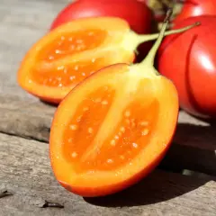 Tomates de palo rojos y brillantes, uno cortado por la mitad revelando su pulpa anaranjada y semillas.
