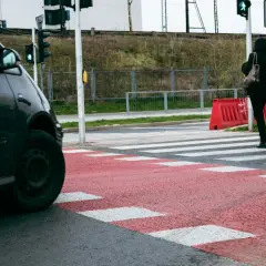 Kobieta przechodzi przez pasy, stosując się do zasady prawej ręki, gdy zielone światło dla pieszych pozwala na ruch.