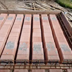 Budowa stropu Ackerman: rzędy pustaków ceramicznych czekają na zalanie betonem, zbrojenie stalowe gotowe do pracy.