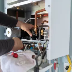 Naprawa kotła gazowego. Technik sprawdza elementy, by upewnić się, czy spalona grzałka szkodzi i czy urządzenie jest bezpieczne.