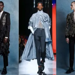 Tres modelos masculinos lucen trajes de alta costura con un aire de la época victoriana: uno con volantes negros, otro con un abrigo azul y un tercero con un traje bordado.