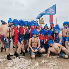 Grupa morsów w niebieskich piórach i maskach pozuje na plaży. Pewnie zastanawiają się, ile stopni ma Bałtyk w styczniu.
