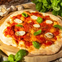 Eine köstliche Pizza Marinara mit Tomatensauce, Knoblauchscheiben und frischem Basilikum auf einem Holzbrett.