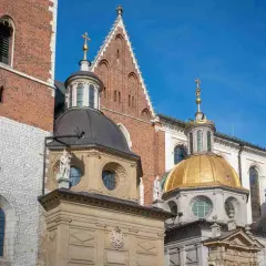 Katedra Wawelska z bliska: ceglana wieża, złota i czarne kopuły, detale architektoniczne.