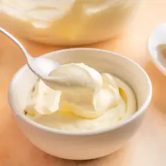 En sked lyfter krämig citronmousse ur en skål. Bredvid ligger citronklyftor, redo att förhöja smaken av citronmousse med lemoncurd.