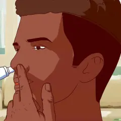 Mężczyzna aplikuje spray do nosa, przykładając końcówkę do jednej z dziurek.