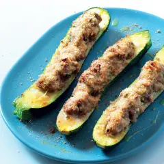 Zucchine tonde ripiene di carne, cotte al forno e servite su un piatto blu.