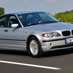 Srebrne BMW E46 lift jedzie po autostradzie. Kierowca w kratę prowadzi auto.