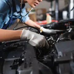 Mechanik w rękawiczkach bada silnik, szukając uszkodzonej pompy wody i jej objawów.