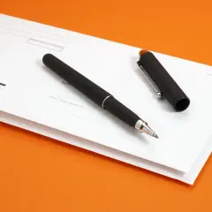 Czarny długopis leży na białej kopercie z polami do wypełnienia. To może być awizo bez numeru przesyłki, czekające na uzupełnienie danych.