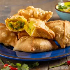 Samosa al forno dorati e croccanti, ripieni di verdure speziate. Un contorno piccante con peperoncino e coriandolo.