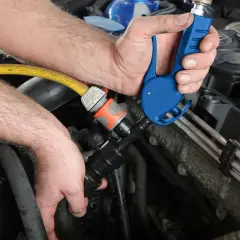 Mechanik podłącza adapter do węża ogrodowego, by przeprowadzić płukanie układu chłodzenia silnika.