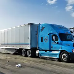Błękitna ciężarówka Gordon Trucking z naczepą, gotowa do podróży door to door.