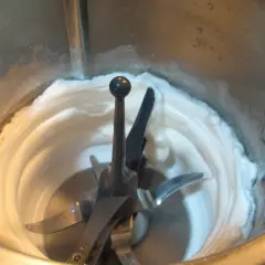 Batidora procesando claras a punto de nieve, creando una textura esponjosa y blanca, lista para un postre.