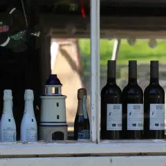 Dwa latarnie morskie, butelki Cava, Prosecco i wina Douce Nature. Różnorodne nazwy win na etykietach.
