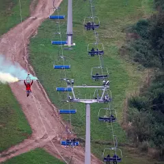 Osoba na tyrolce z kolorowym dymem, obok wyciągu krzesełkowego. To może być najdłuższa tyrolka w Polsce!
