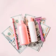 Rosa Rasierer, Zahnbürste und Kosmetikflaschen auf 100-Dollar-Scheinen. Ein Symbol für den "Pink Tax", der Frauen mehr kostet.