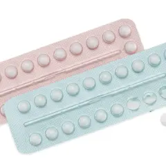 Dwie blistry tabletek antykoncepcyjnych, różowy i niebieski, z kilkoma brakującymi tabletkami.