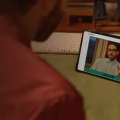 Uomo guarda un video su tablet. Sullo schermo, un uomo con occhiali parla, forse dando uno bravo recensioni.