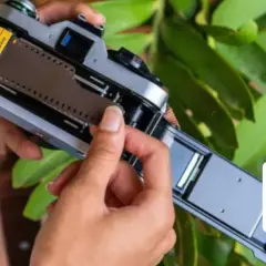 Hands loading a 36-exposure film into a vintage camera. The film roll is visible, ready to capture memories.