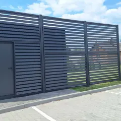 Nowoczesne ogrodzenie z drzwiami, z widoczną odległością ogrodzenia od drogi gminnej wewnętrznej.