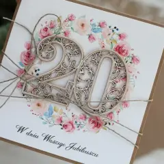 Elegancka kartka z napisem "W dniu Waszego Jubileuszu" i ażurowymi cyframi "20" na tle kwiatowej girlandy. Idealna na 20 rocznicę ślubu życzenia.