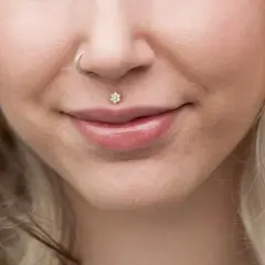 Delikatny kolczyk w ustach w kształcie kwiatka z cyrkoniami, ozdabiający środek górnej wargi.