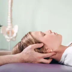 Delikatna terapia cranio sacralna u młodej dziewczyny. Terapeuta delikatnie uciska jej głowę, wspierając proces leczenia.