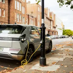 Coches eléctricos noticias: un Hyundai Ioniq 5 cargando en una calle de Londres, con edificios de ladrillo y hojas caídas.
