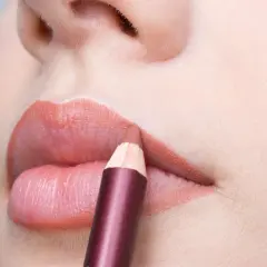 Close-up of lips with a lip liner pencil being applied.