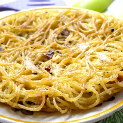 Una dorata frittata di scammaro, con spaghetti croccanti e pezzetti di pancetta, pronta per essere gustata.