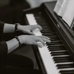 Dłonie grające na pianinie, w eleganckim stroju, tworzą niepowtarzalny styl w jazie.