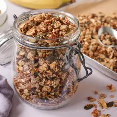 Ein Glas voller knusprigem, selbstgemachtem Granola ohne Zucker, mit Nüssen und Kernen. Perfekt für ein gesundes Frühstück.
