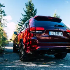 Ciemnoczerwony Jeep Grand Cherokee Trackhawk na tle jesiennego krajobrazu.