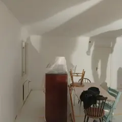 Rummet är nymålat vitt, möbler är täckta med plast. Skuggor på väggarna antyder att det är en pågående renovering, vilket väcker frågan: hur lång tid tar det att måla ett rum?