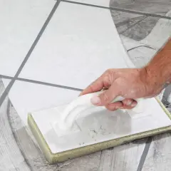 Main tenant, quand nettoyer carrelage après joint, utilise une éponge pour enlever l'excès de mortier.