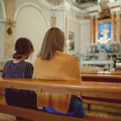 Dwie osoby siedzą w kościele, zastanawiając się, kto może zostać świadkiem bierzmowania.