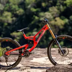 A bright red Santa Cruz V10 downhill bike sits on rocks, ready for its next review.