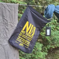 Czarny worek na śmieci z napisem "NO TRACE" przypomina o zasadach "leave no trace" podczas wypoczynku na łonie natury.