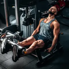 Mann trainiert Beine an einer Maschine, die Kraft durch Push- und Pull-Bewegungen aufbaut.
