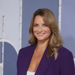 Dagmara Kaczmarek Szałkow w fioletowej marynarce, znana z Faktów TVN, uśmiecha się do kamery.