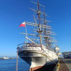 Duma polskiego żeglarstwa, żaglowiec "Dar Pomorza", cumuje w porcie. Biało-czerwona flaga dumnie powiewa na maszcie.
