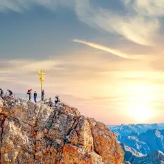 Menschen auf dem Gipfel der Zugspitze mit goldenem Kreuz. Die Zugspitze Aufstieg Dauer ist lang, aber die Aussicht ist es wert.