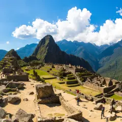 Machu Picchu, dawna twierdza Inków, wznosi się wśród zielonych gór. Turyści zwiedzają ruiny, podziwiając dzieło Inków.