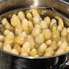 Espárragos blancos cocinándose en una olla.