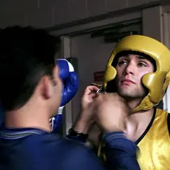 A boxer in a yellow headguard and vest gets ready for the fight, wondering how many rounds in boxing he'll endure.